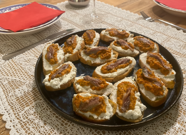 Crostini mit Paprika, Sardellen und Ricotta auf einem Keramikteller
