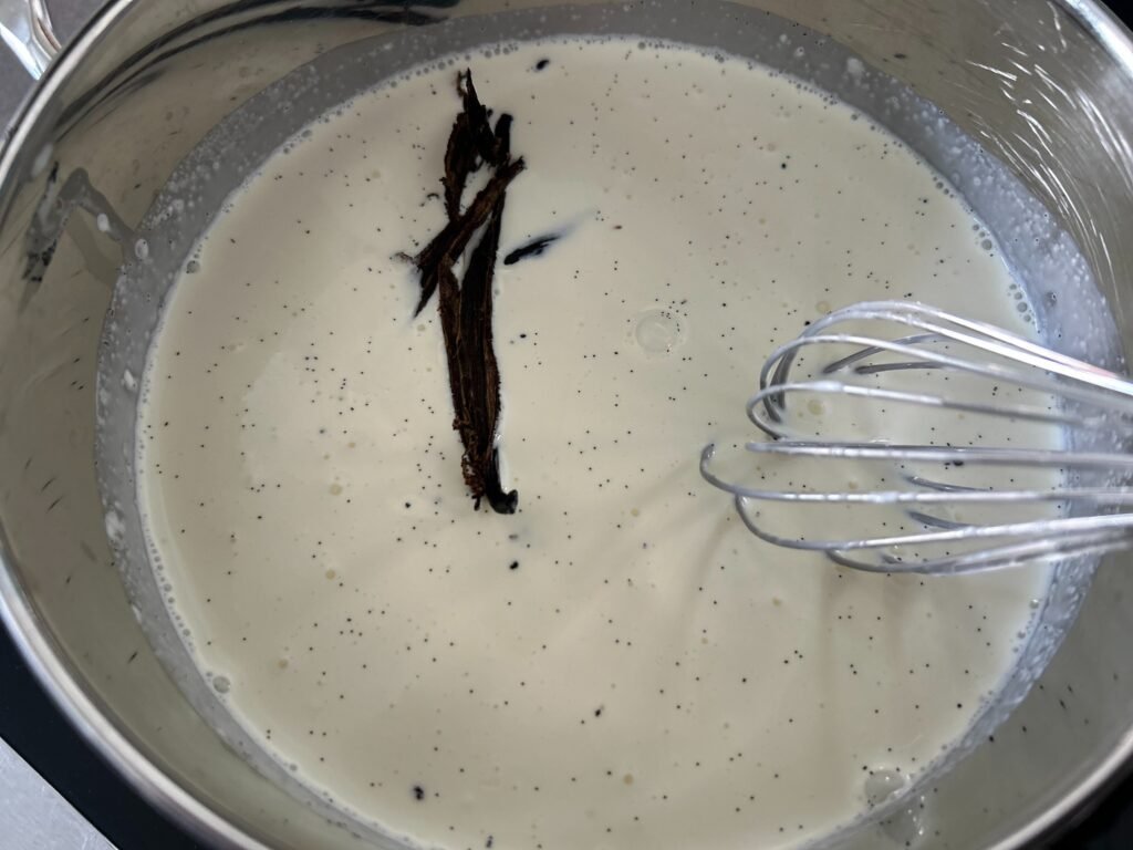 Vanilleschote schwimmt in einem Topf mit sahniger Flüssigkeit