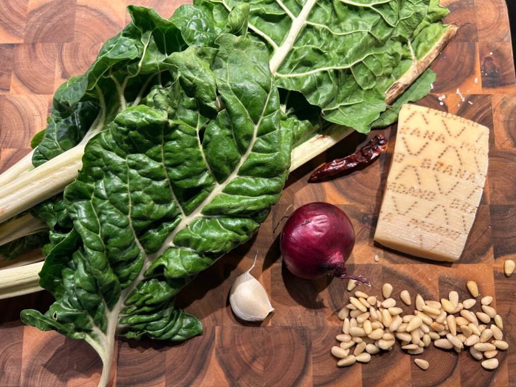 Zutaten für Mangoldpesto auf einem Olivenholzbrett