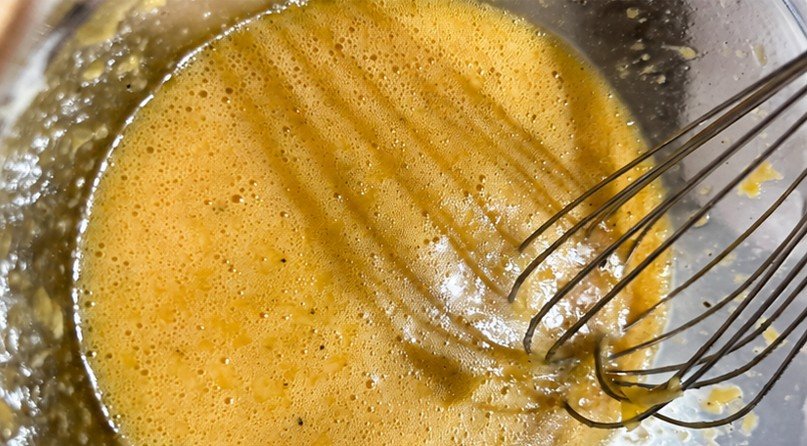 Ei-Pecorino-Creme für Carbonara wird in einer Glasschüssel mit einem Schneebesen verrührt