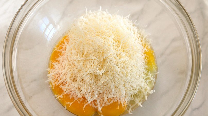 In einer Glasschüssel werden Eigelb, Pecorino und Pfeffer vermengt