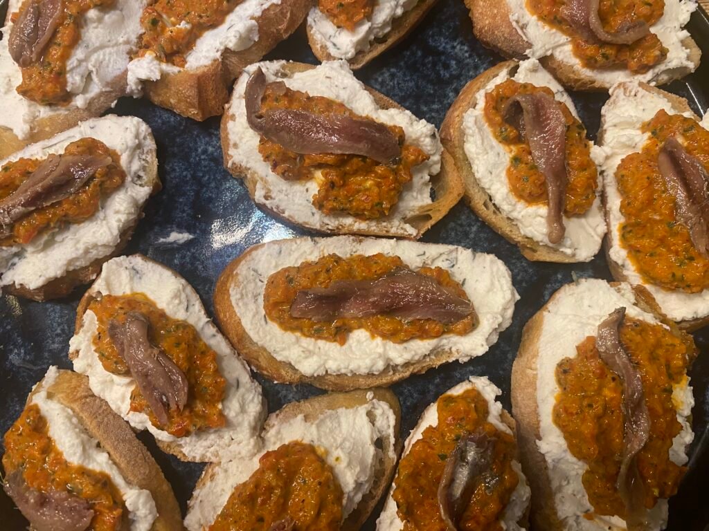 Crostini mit Ricotta und Sardellen auf Keramikteller angerichtet