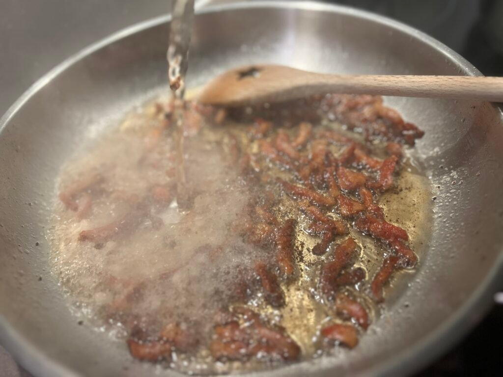 Guanciale wird mit Wein abgelöscht