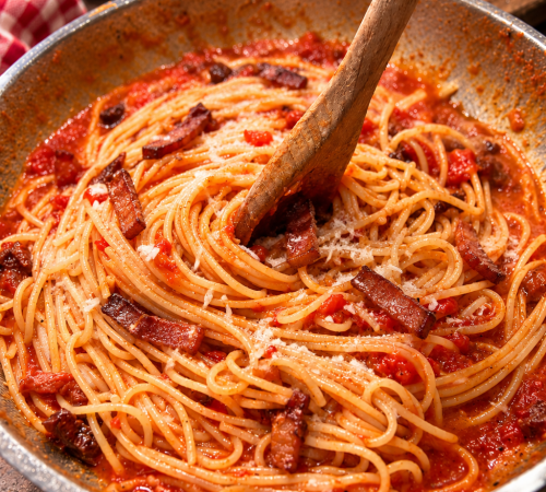 Spaghetti werden in einer Pfanne mit Tomatensauce Guanciale und Pecorino vermengt