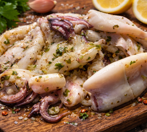 Calamari in ganzen Tuben ausgebreitet auf einem Holzbrett in leichter Kräutermarinade