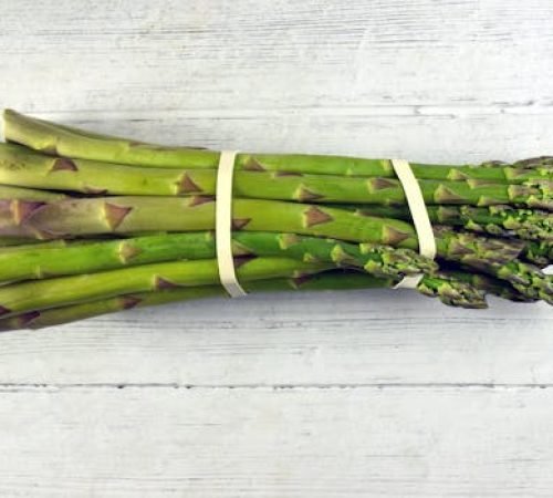A close-up view of a fresh asparagus bundle on a rustic wooden background, highlighting its vibrant green color.